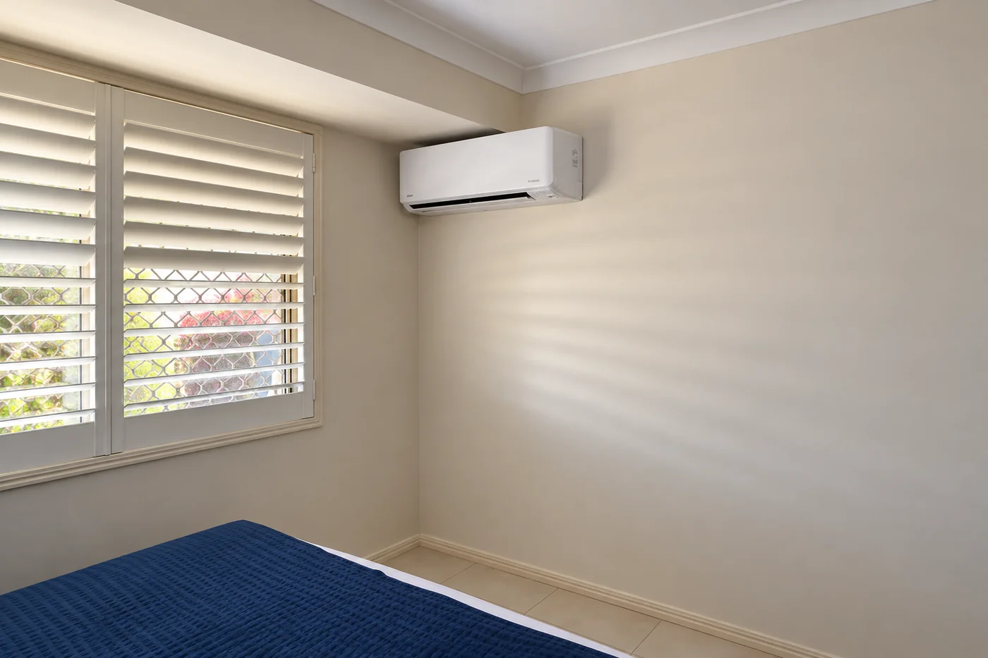 Wall-mounted split system air conditioner beside a bedroom window